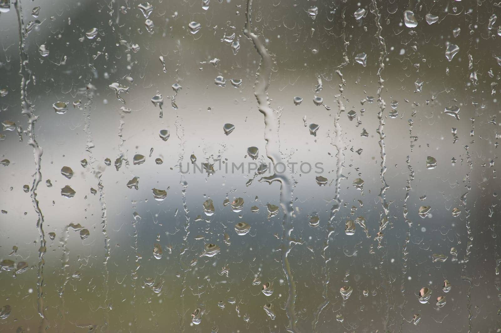 Window glass surface that has a textured pattern created by several water droplets of different sizes