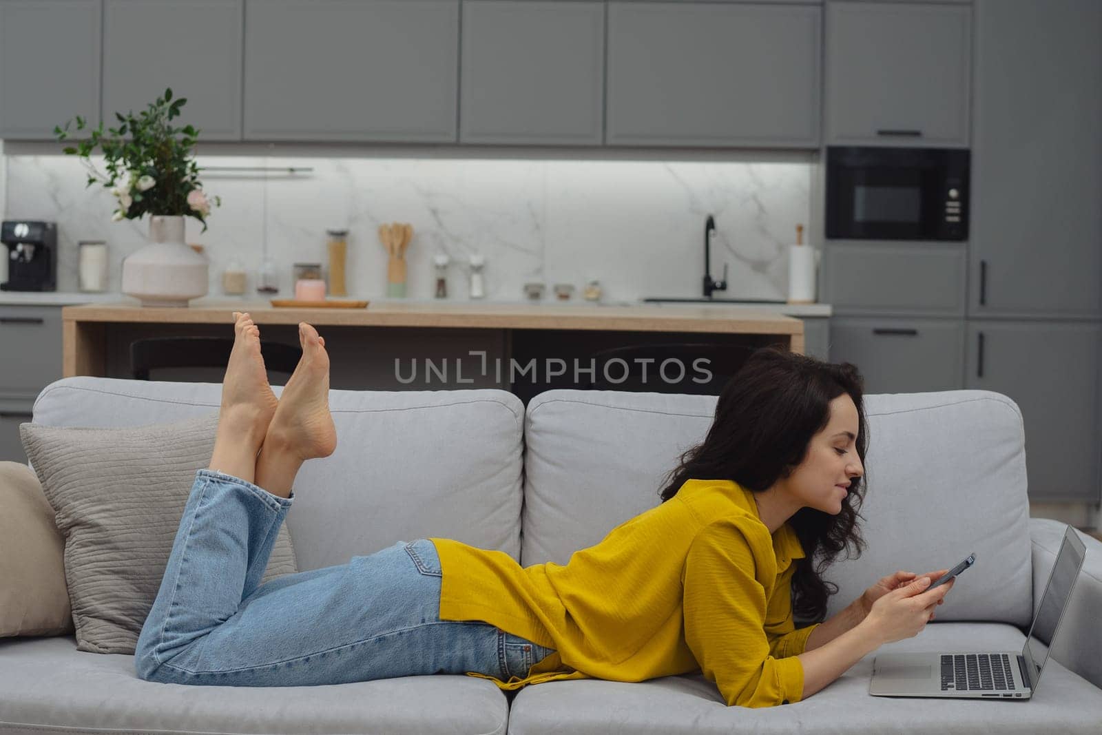 Thoughtful young woman in eyewear using computer while sitting on the sofa at home. High quality photo