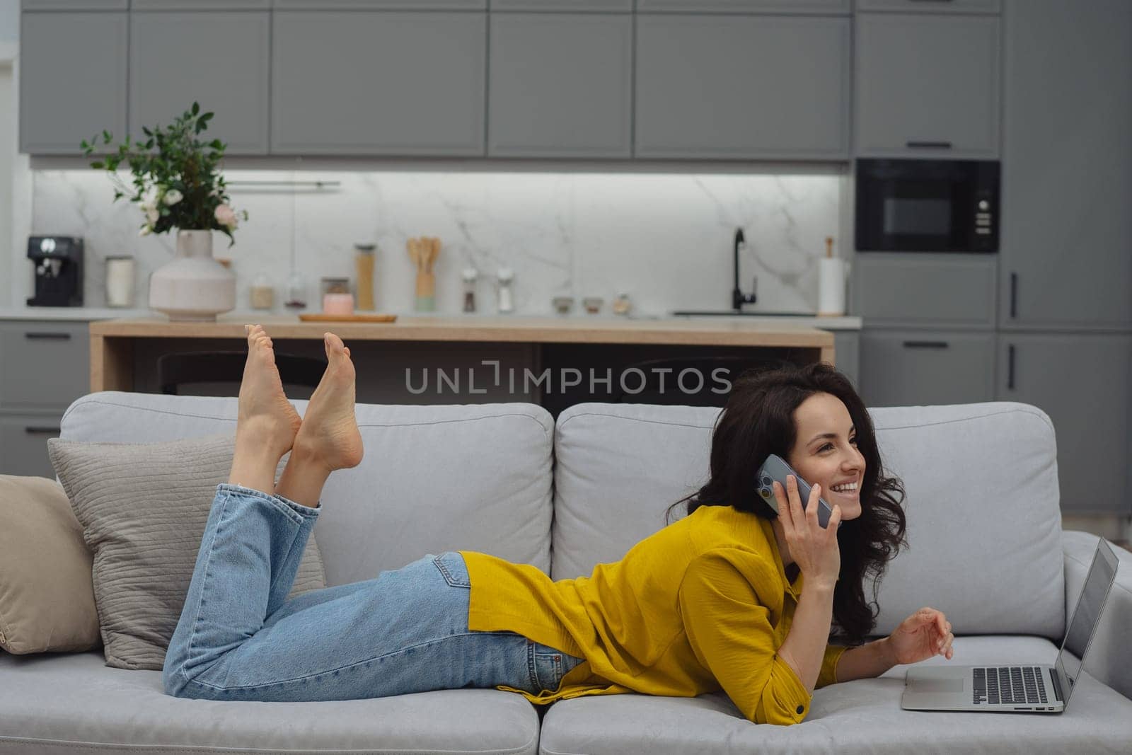 Thoughtful young woman in eyewear using computer while sitting on the sofa at home. High quality photo