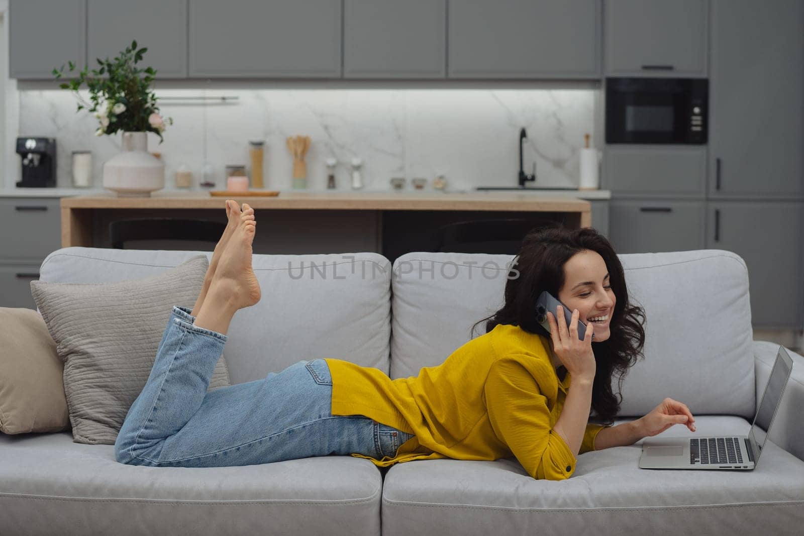 Thoughtful young woman in eyewear using computer while sitting on the sofa at home. High quality photo