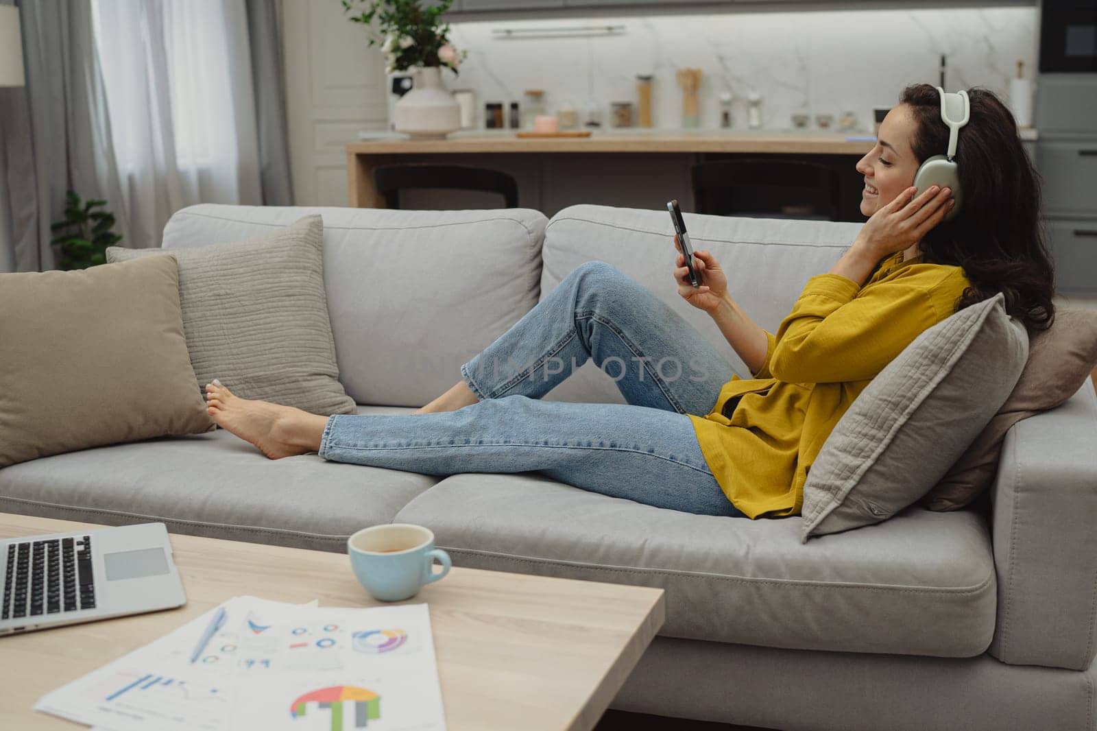 Thoughtful young woman in eyewear using computer while sitting on the sofa at home. High quality photo