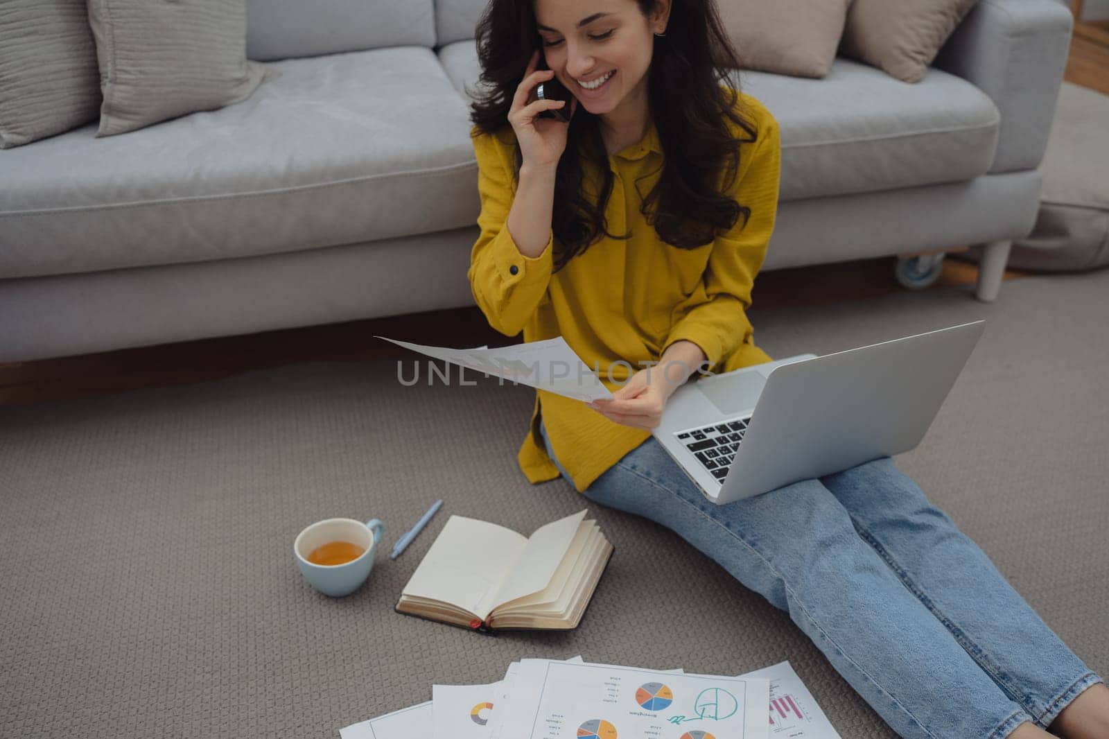 Thoughtful young woman in eyewear using computer while sitting on the sofa at home. High quality photo