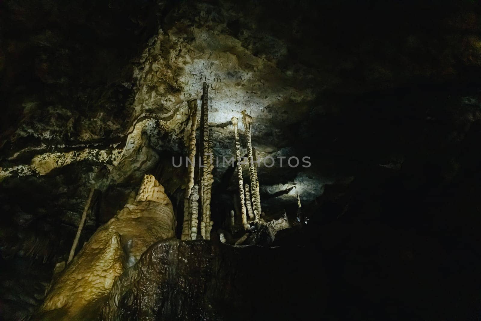 Beautiful view of natural long and thin stalactites in a dark underground cave in de Duinen De Haan, Belgium, side view close-up.