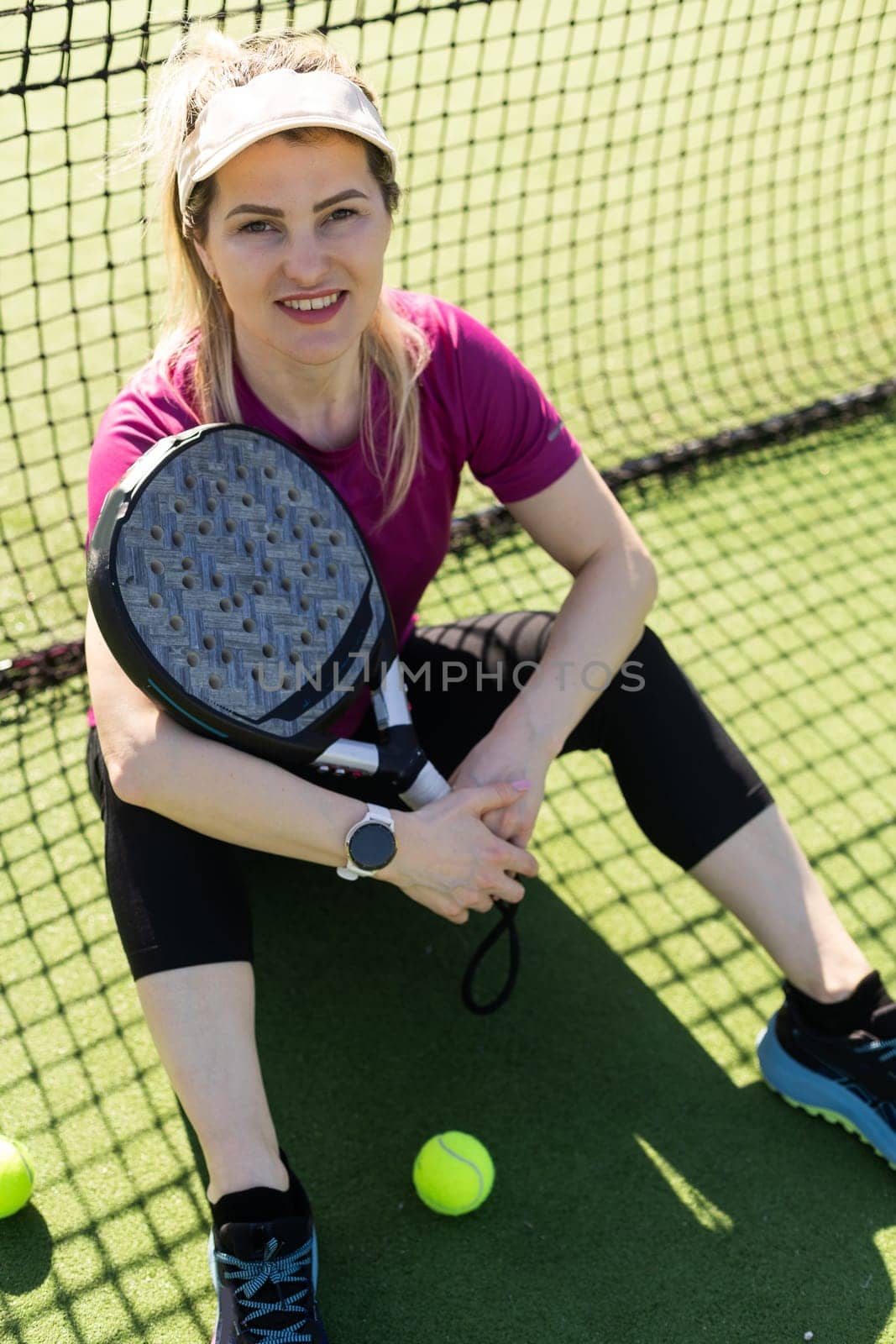 Sporty european woman padel tennis player trains on the outdoor court using a racket to hit the ball. High quality photo