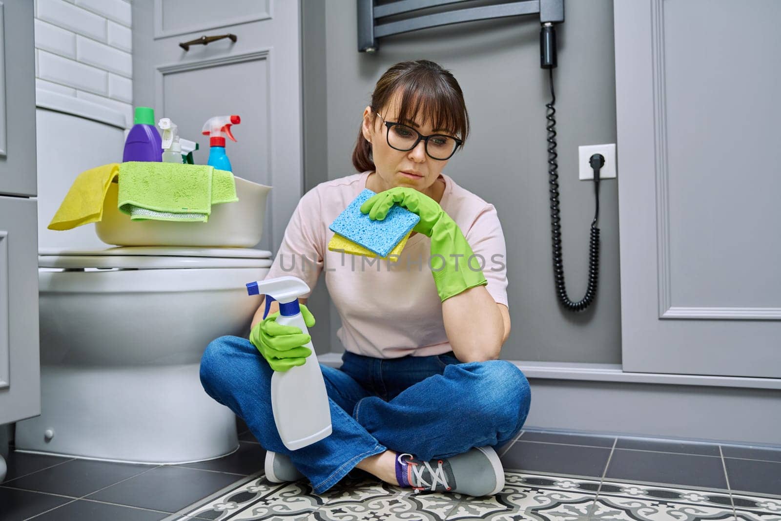 Tired woman sitting on the floor after cleaning the bathroom by VH-studio