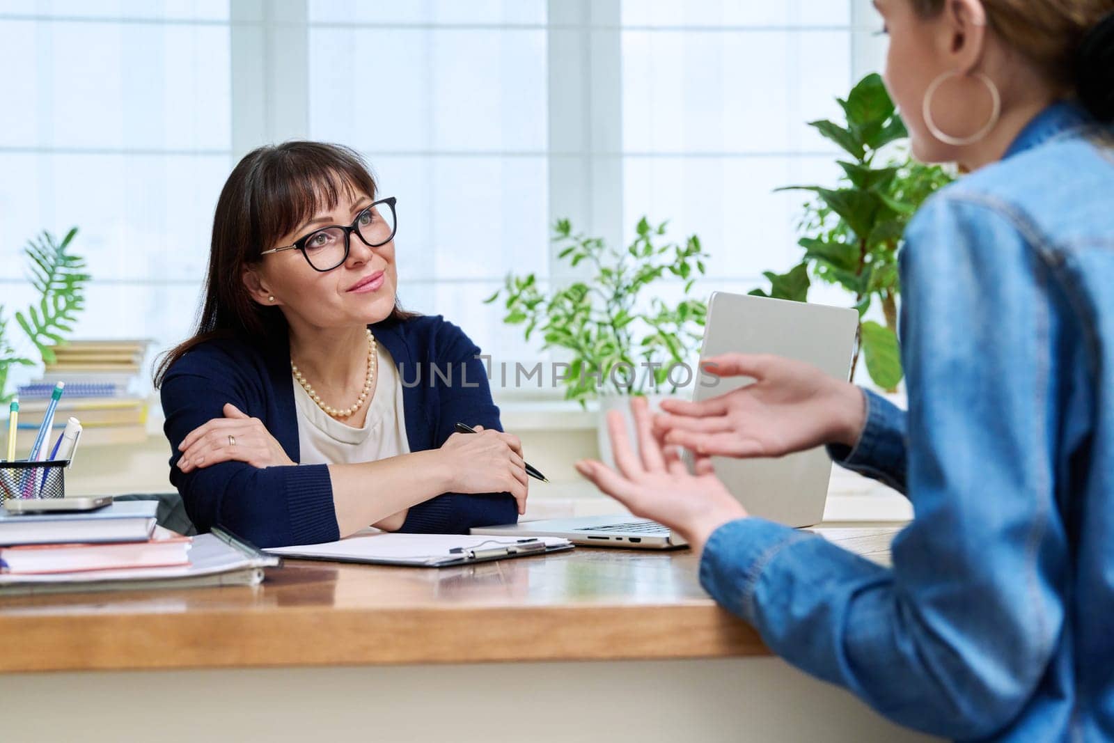 Female psychologist therapist working with young teen girl sitting in office. Teenage female student at therapy meeting with counselor. Psychology therapy psychotherapy youth mental health treatment