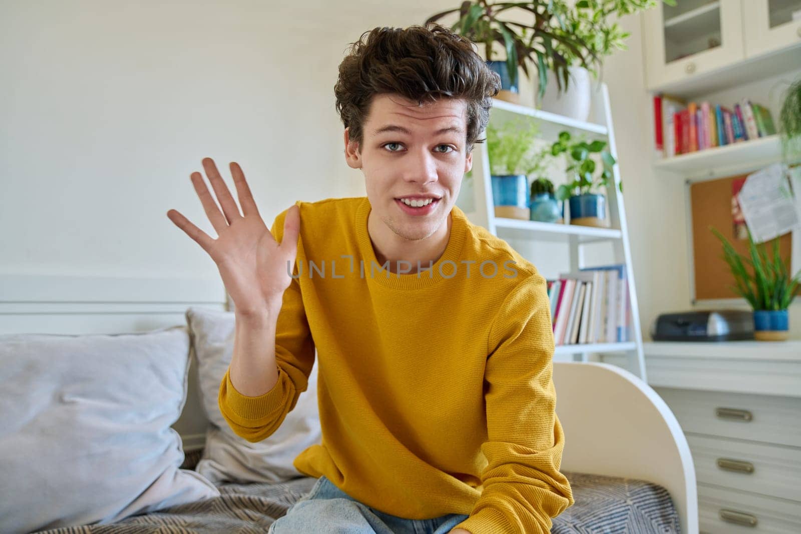 Web cam view of young handsome guy 19-20 years old waving at camera in home. Influencer recording video for vlog blog, university college student studying online, video chat call conference