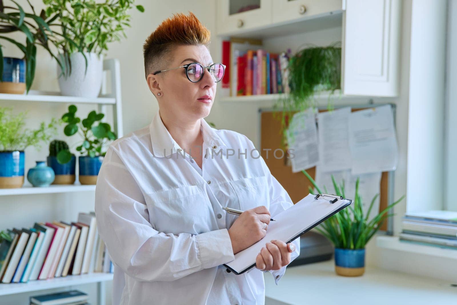 Portrait of serious female psychotherapist with clipboard at workplace in office. Professional mental therapist counselor psychologist social worker behavior. Health care services, treatment