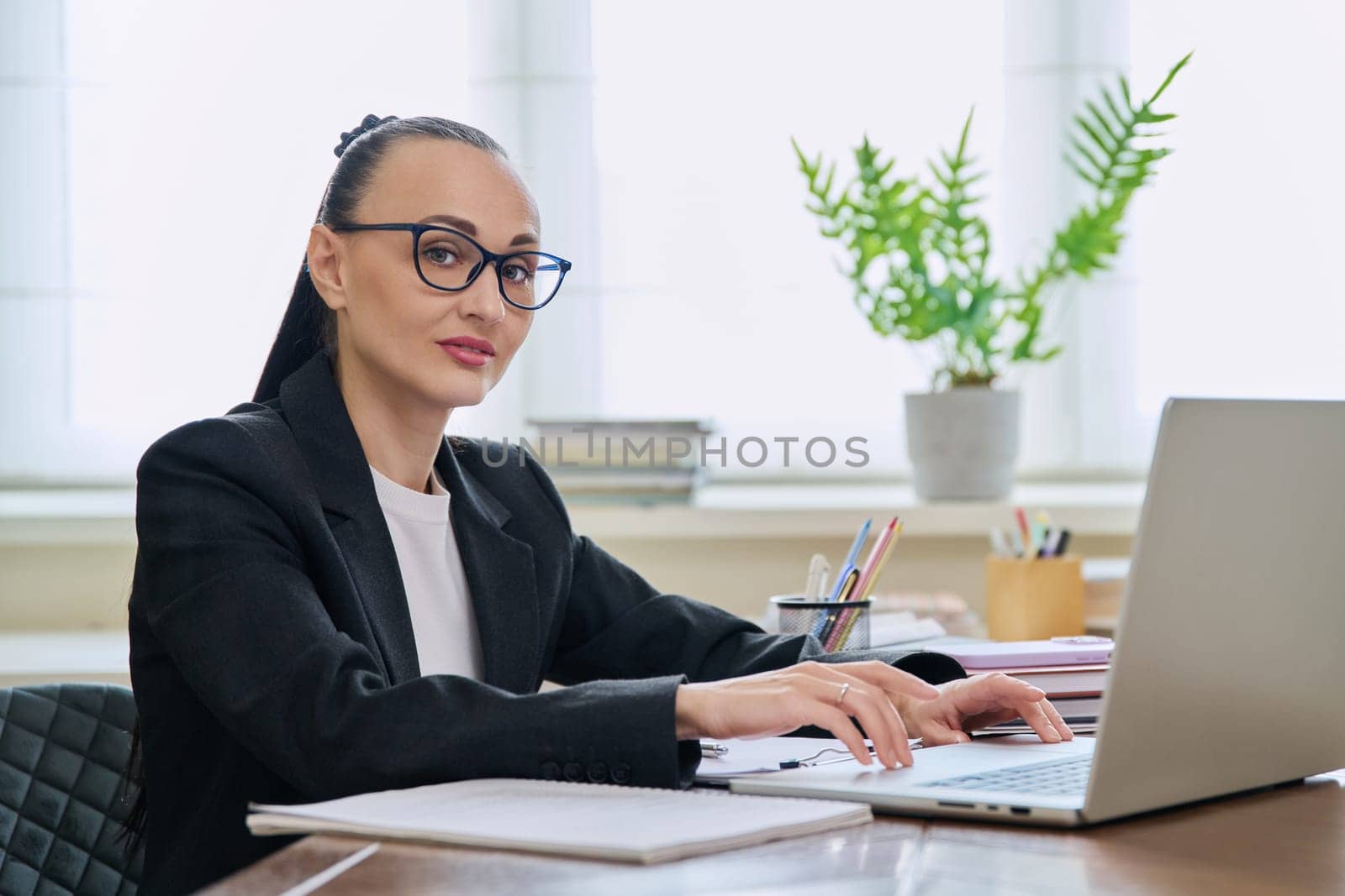 Portrait of business woman sitting at workplace with computer by VH-studio