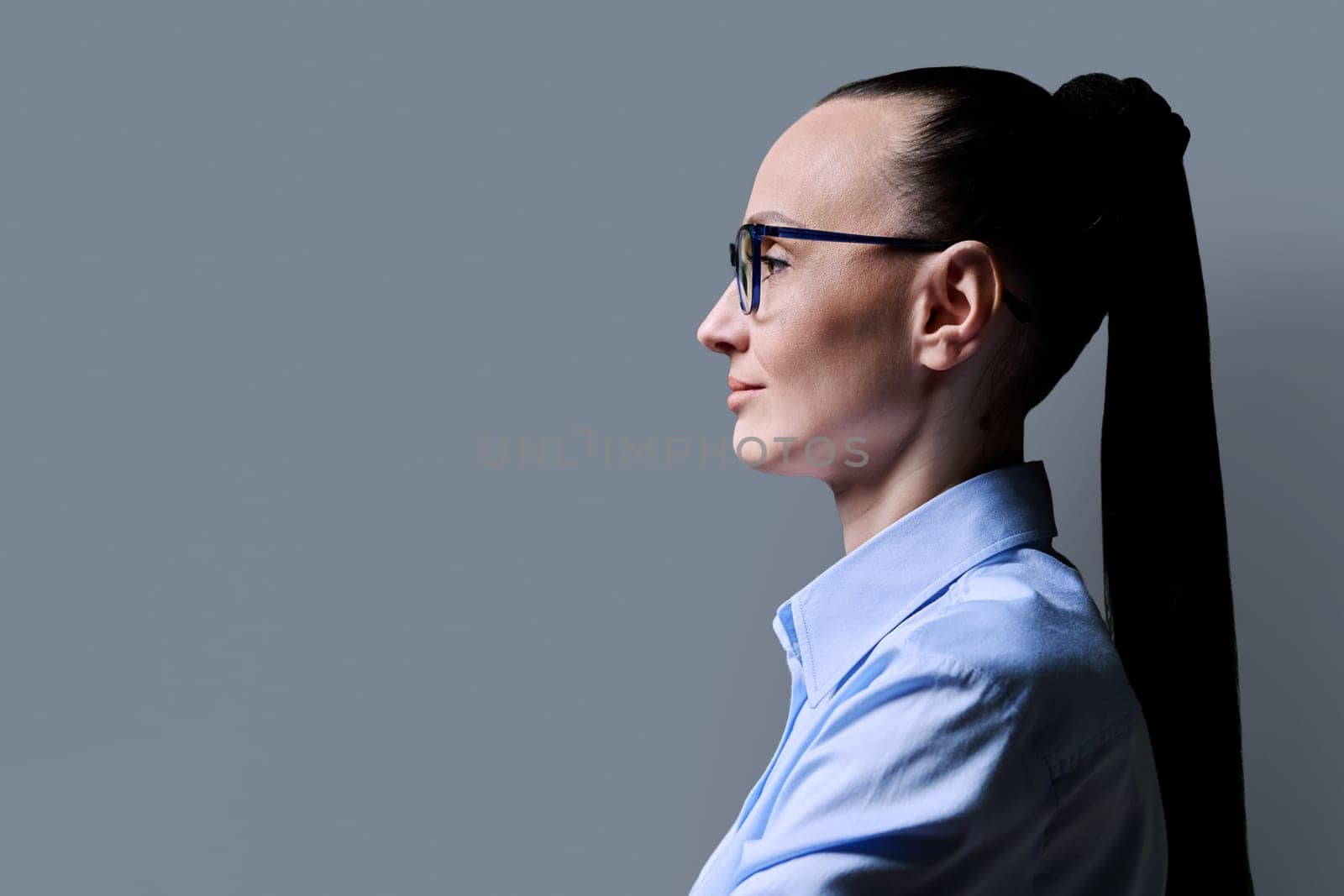 Profile view of 30s serious woman, gray background, copy space by VH-studio