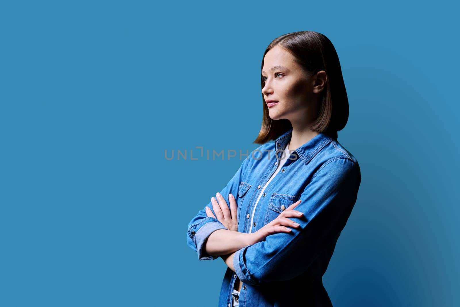Profile portrait of young confident woman on blue background by VH-studio