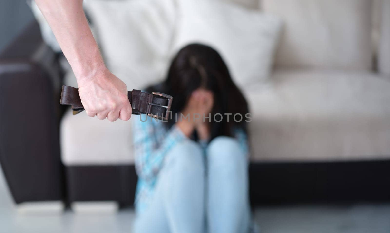 Man holds belt in fist against background of crying woman closeup by kuprevich