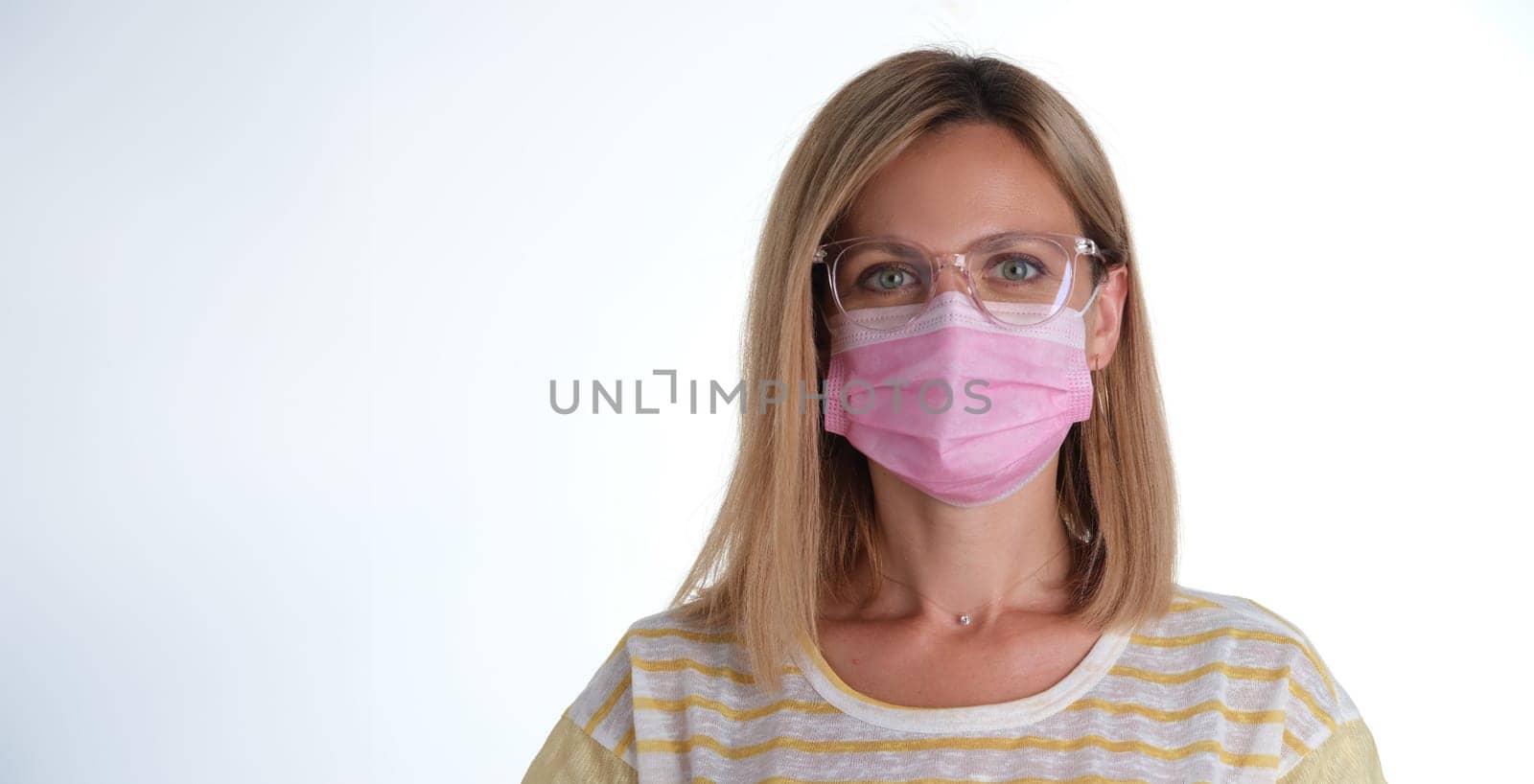 Portrait of young beautiful woman in pink protective medical mask and glasses closeup by kuprevich