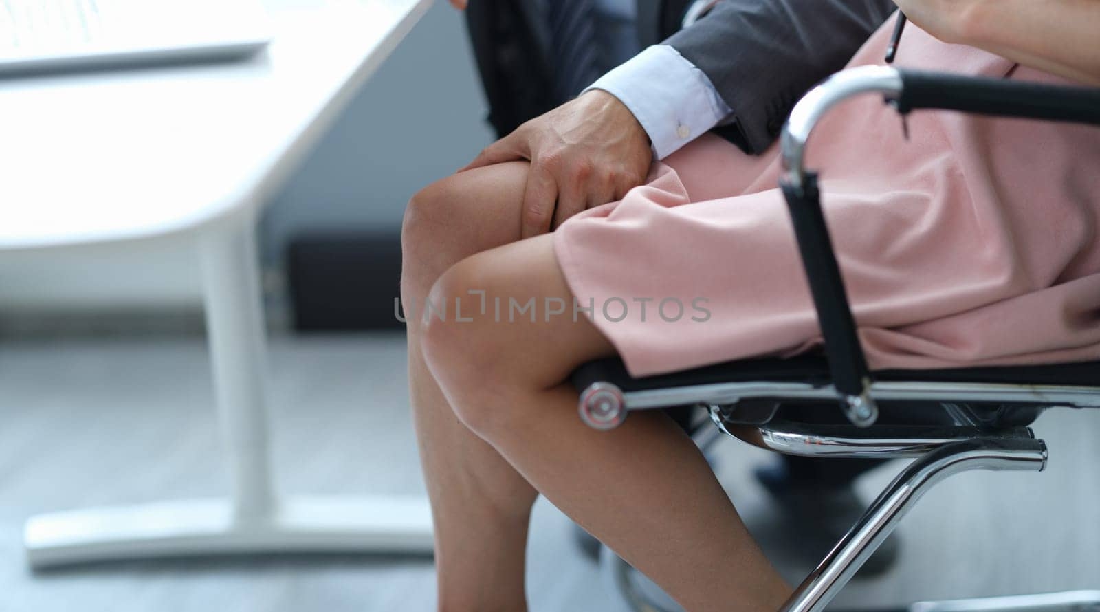 Businessman will put his hand on woman leg under table. Sexual harassment at work concept