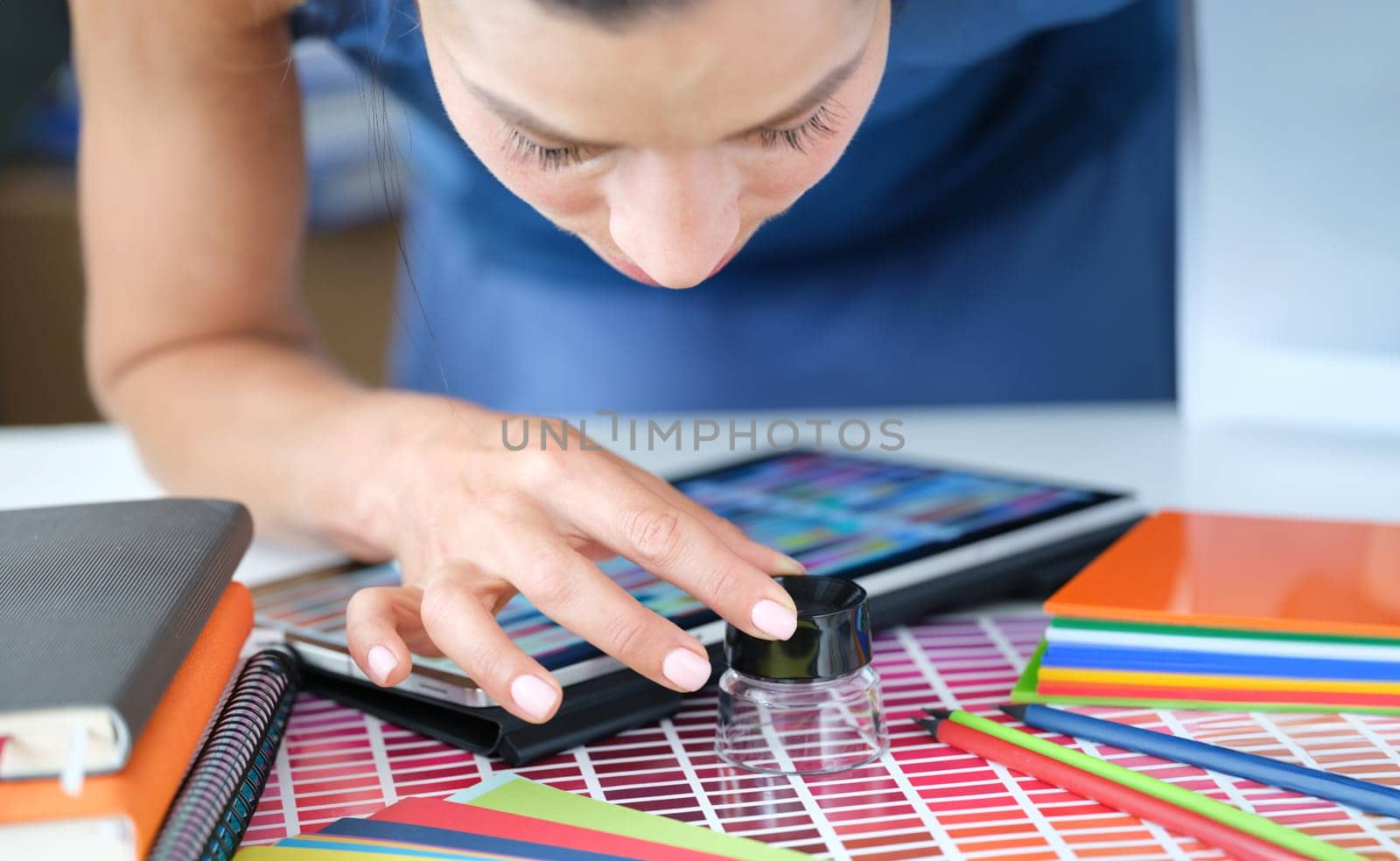 Woman designer looks through magnifying glass at color palette of red shades by kuprevich