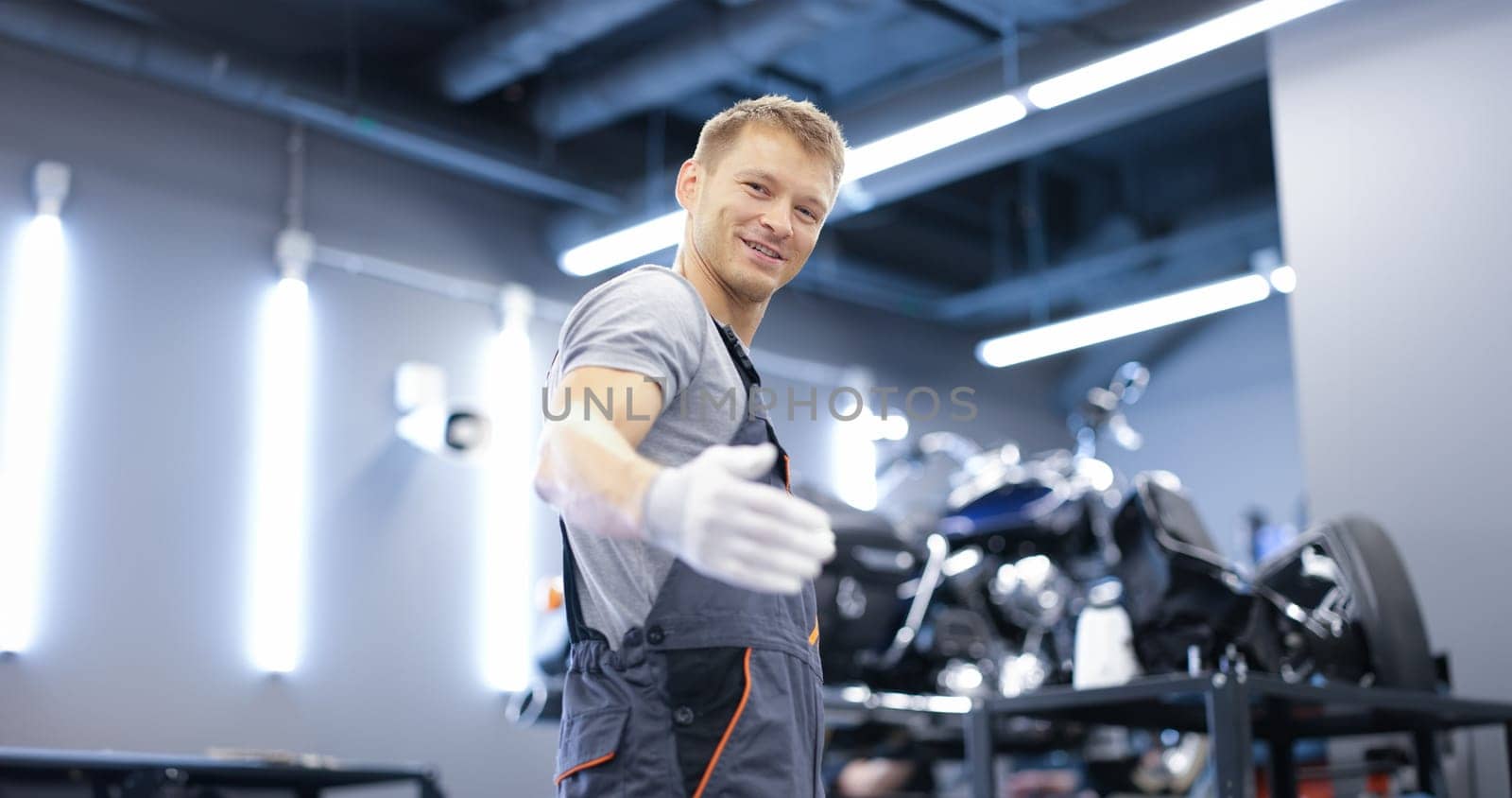 Smiling young car mechanic stands in workshop closeup by kuprevich