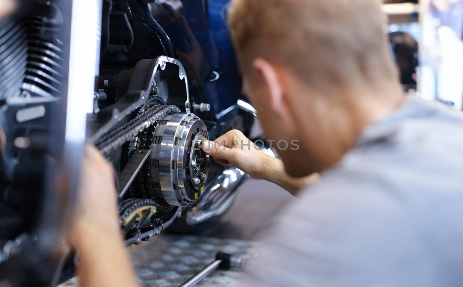 Mechanic repairs motorcycle engine in workshop closeup by kuprevich