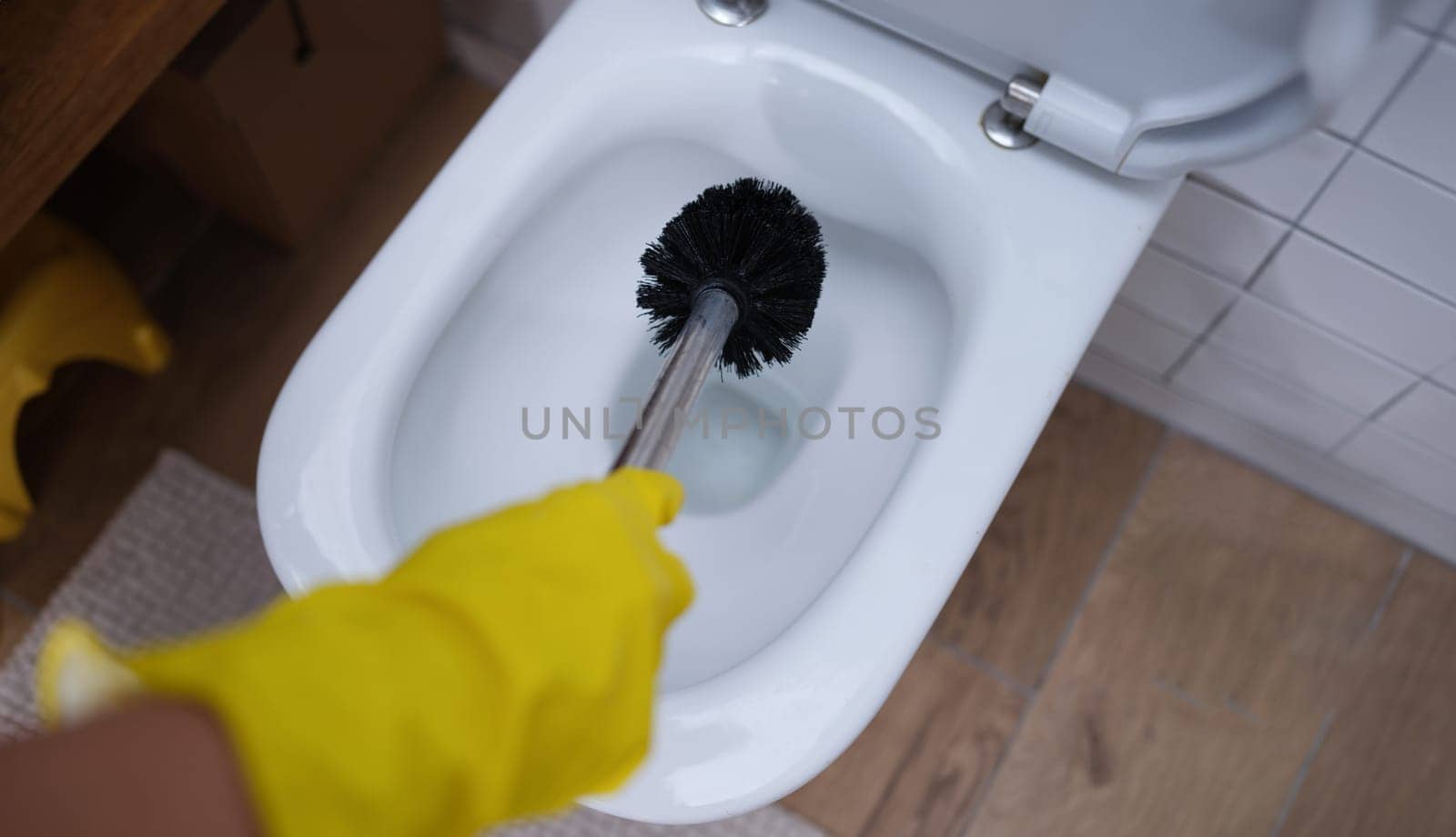 Gloved hand is cleaning toilet with brush closeup by kuprevich