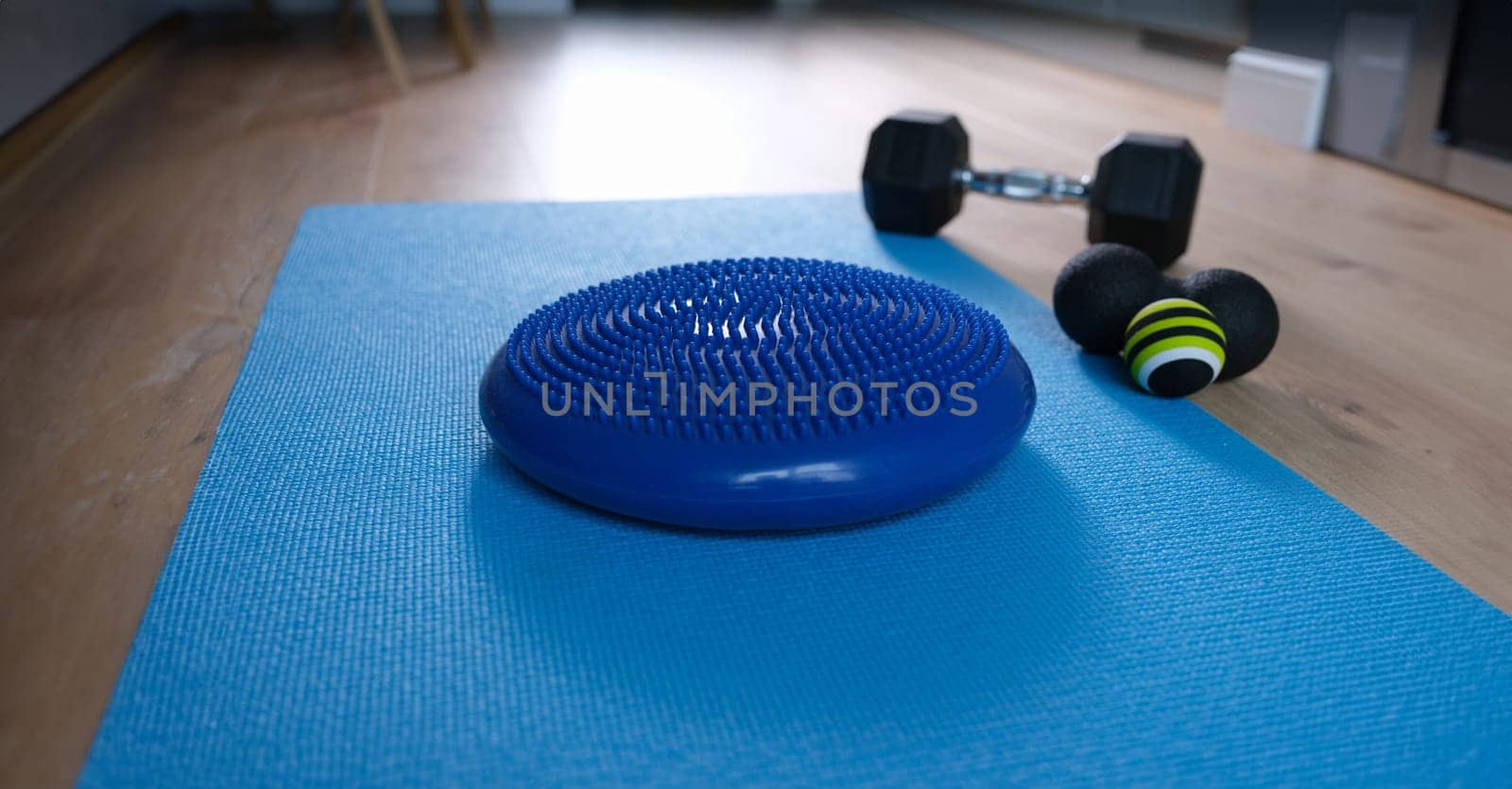 Blue balance cushion lying on mat near dumbbells and roll ball home closeup by kuprevich