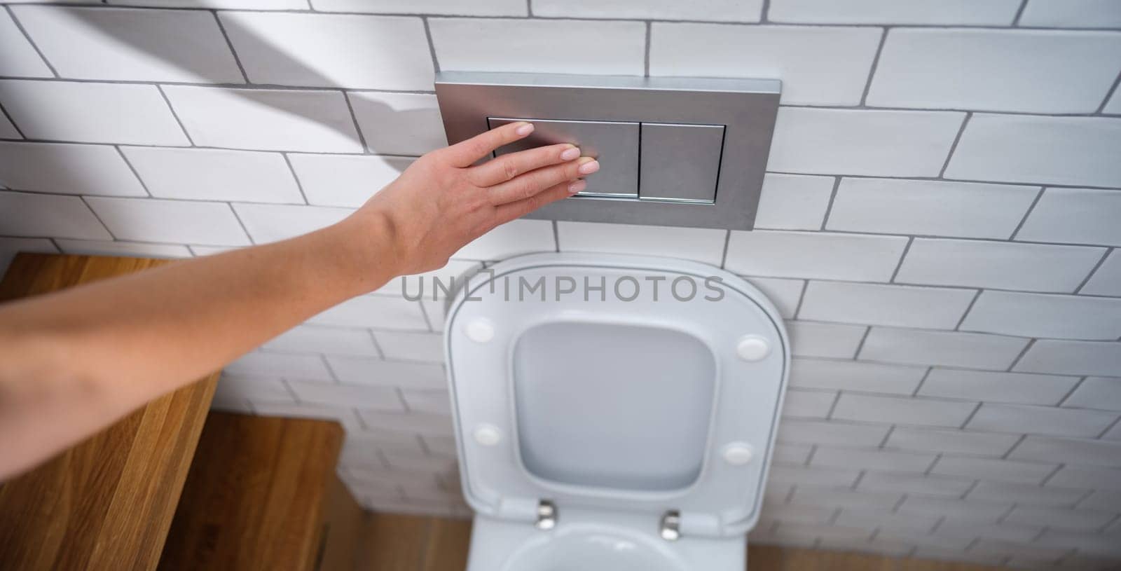 Female hand presses toilet flush button. Installation flush plates concept