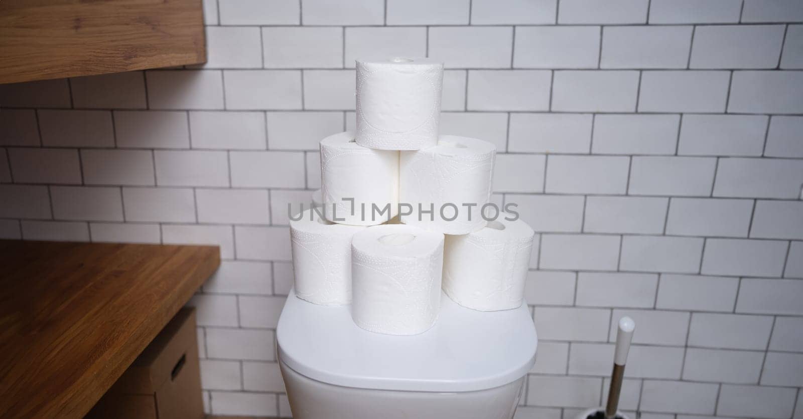 Stack of toilet paper stands on white toilet in bathroom closeup by kuprevich