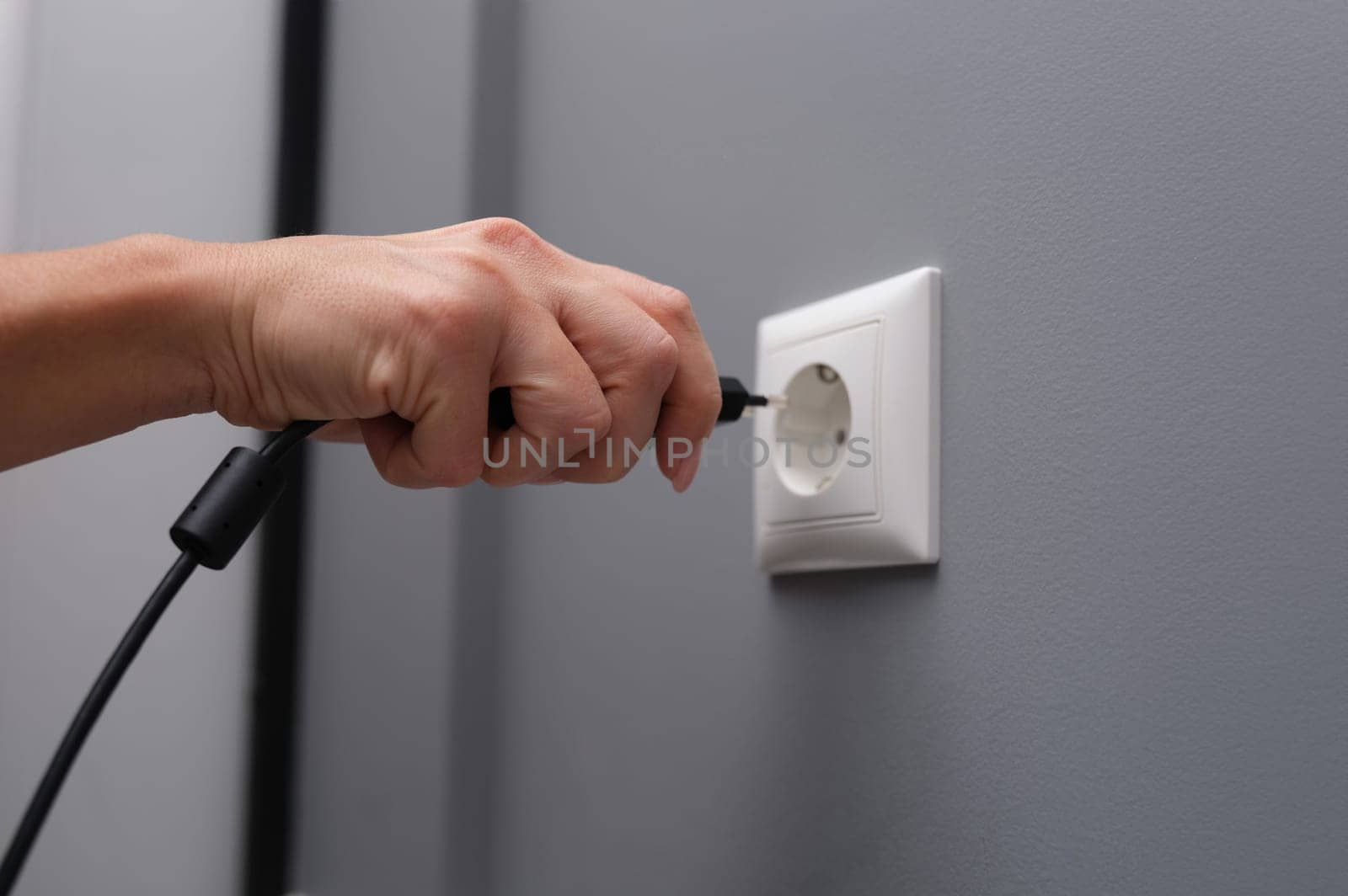 Woman hand inserts electrical plug into outlet closeup by kuprevich