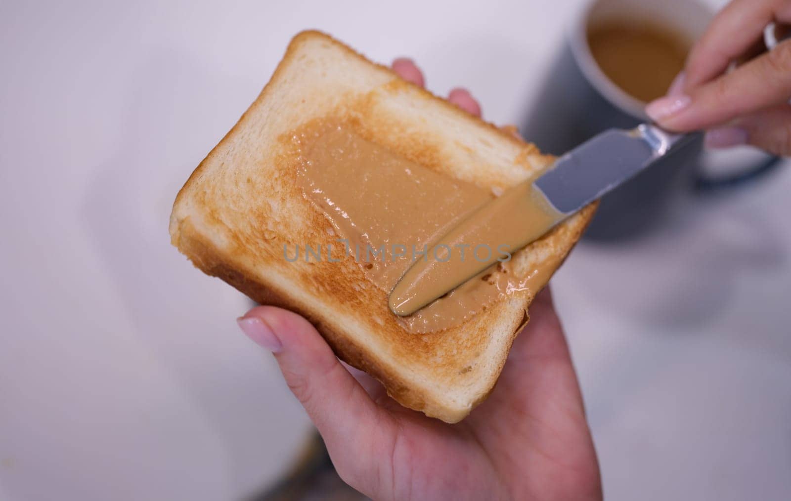 Woman spreading peanut butter on toast closeup. Quick breakfast concept