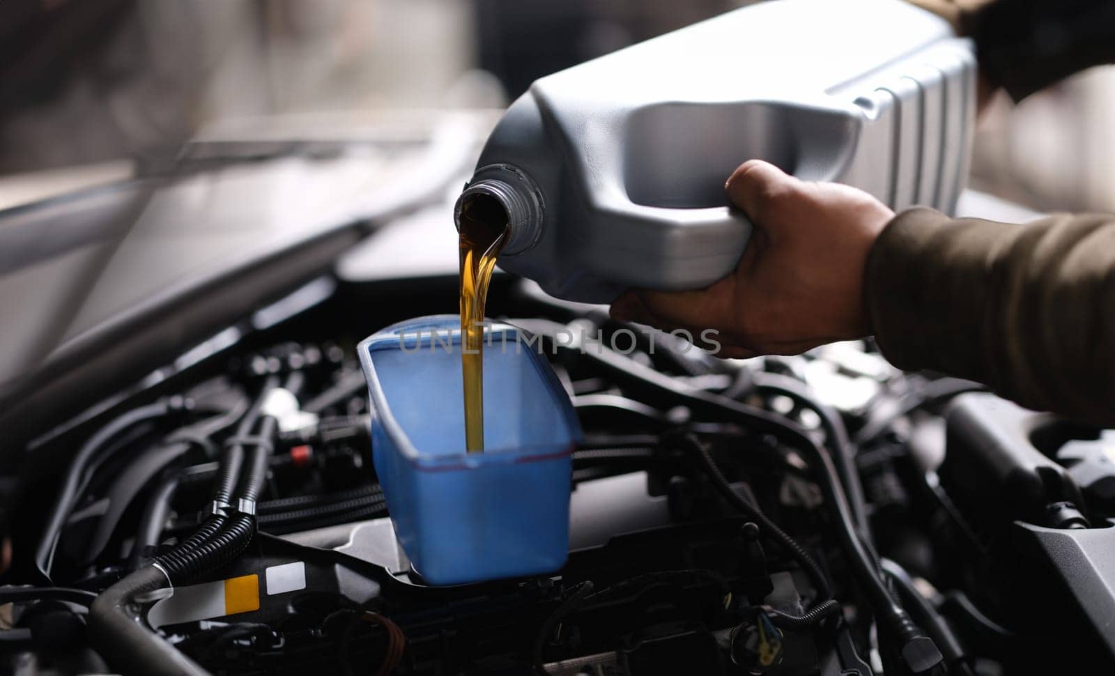 Master repairman pouring motor oil into car engine closeup by kuprevich