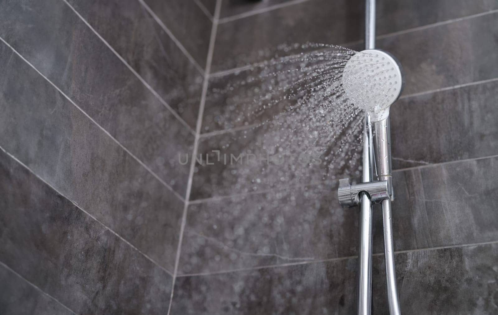Trickles of water flowing from shower head in bathroom closeup by kuprevich