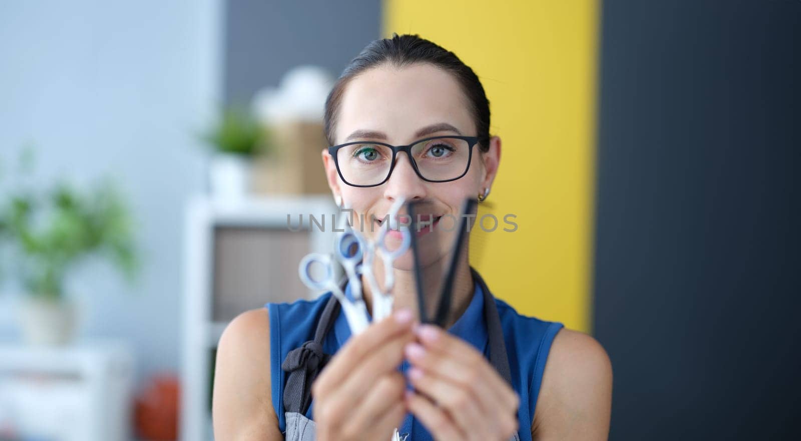 Portrait of woman hairdresser holding scissors and comb in hand. Hairdresser training concept