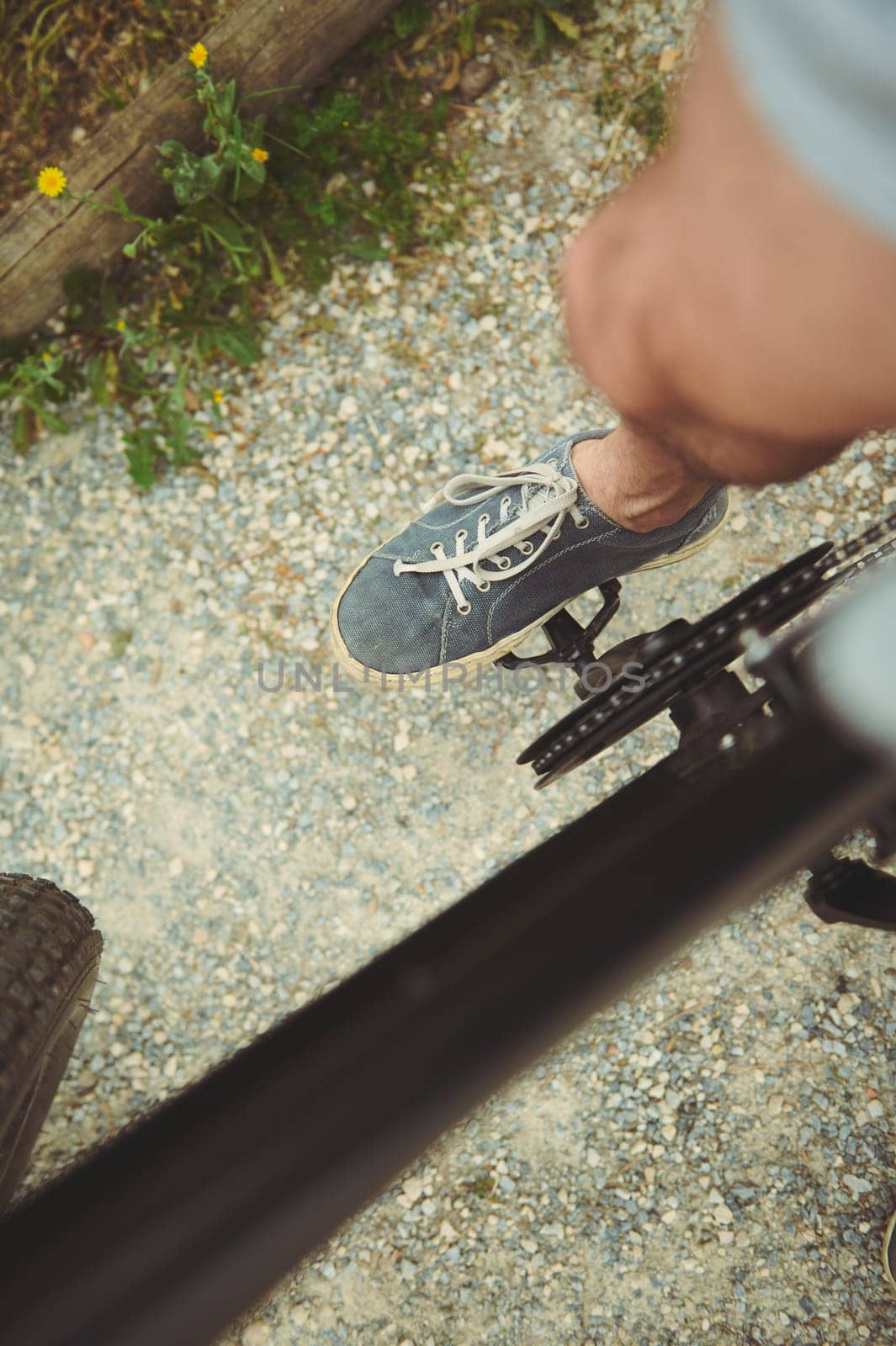 Cyclist point of view. Close-up top view of male foot in denim sneakers on the electric bike pedal, riding outdoors by artgf