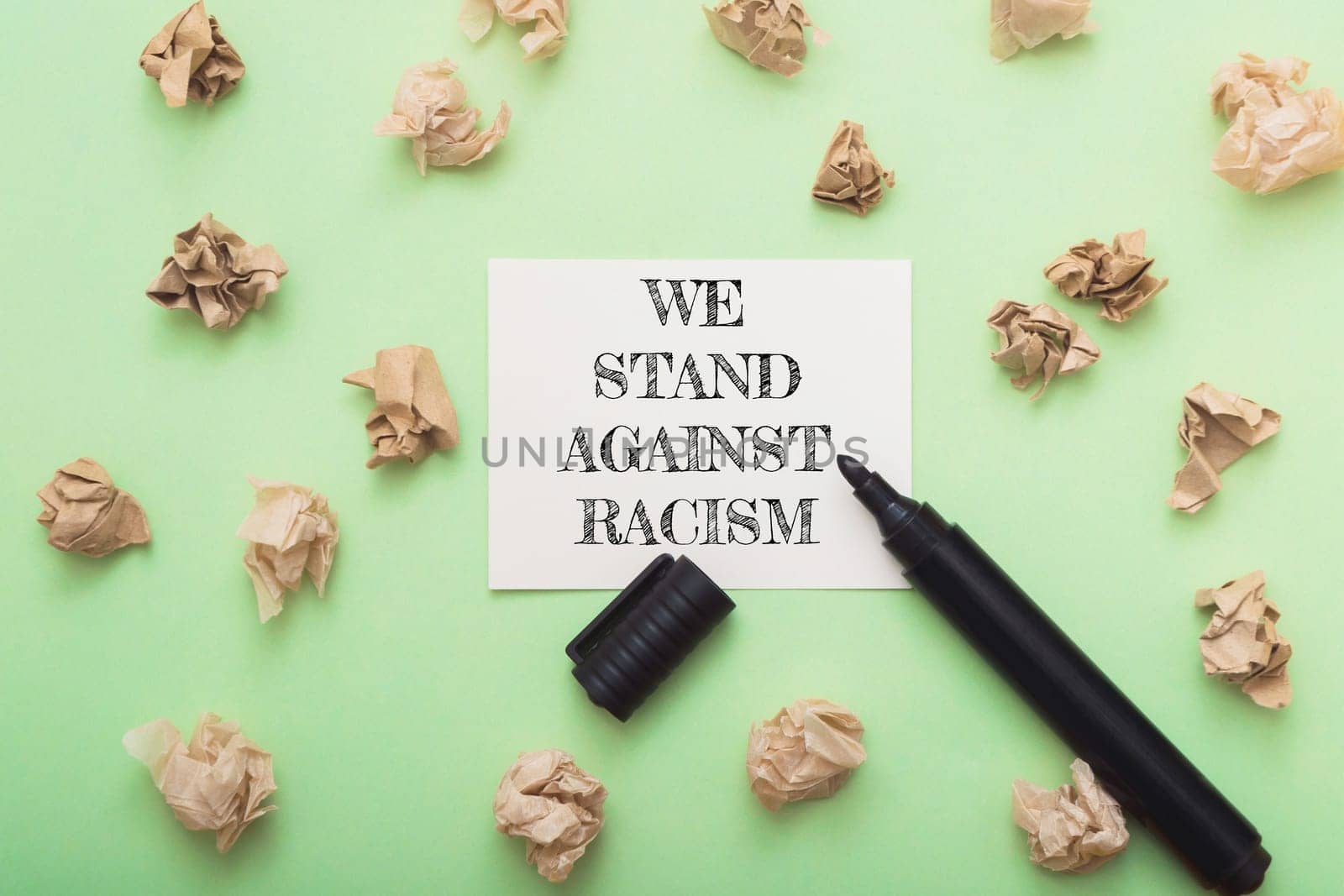 A black marker is on a green background with a piece of paper that says We stand against racism.
