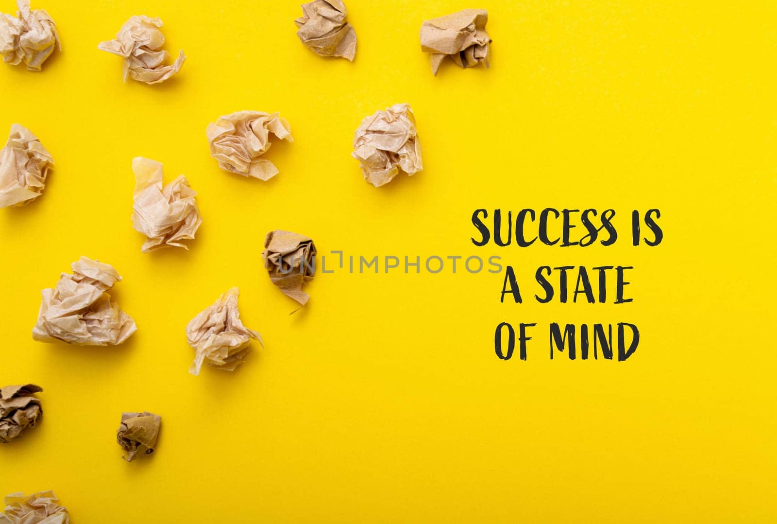 A motivational concept depicted with a yellow background and a cluster of crumpled paper spread across it.