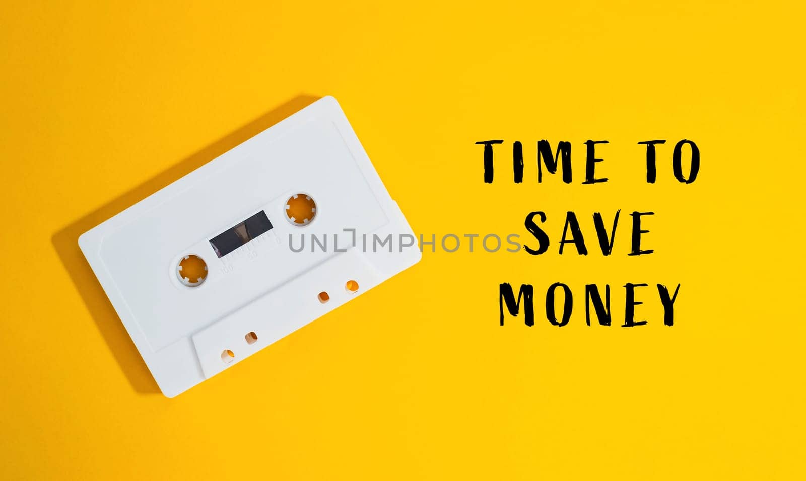 A white cassette tape is on a yellow background with the words Time to save money written below it