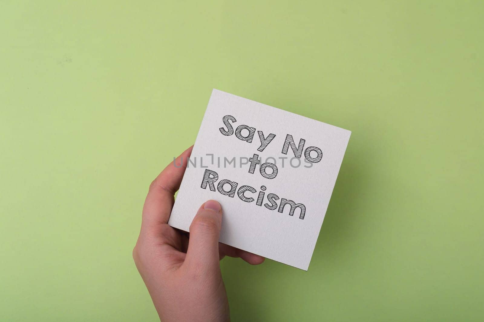 A hand holding a piece of paper that says Say No to Racism. The image conveys a strong message against racism and encourages people to take a stand against it