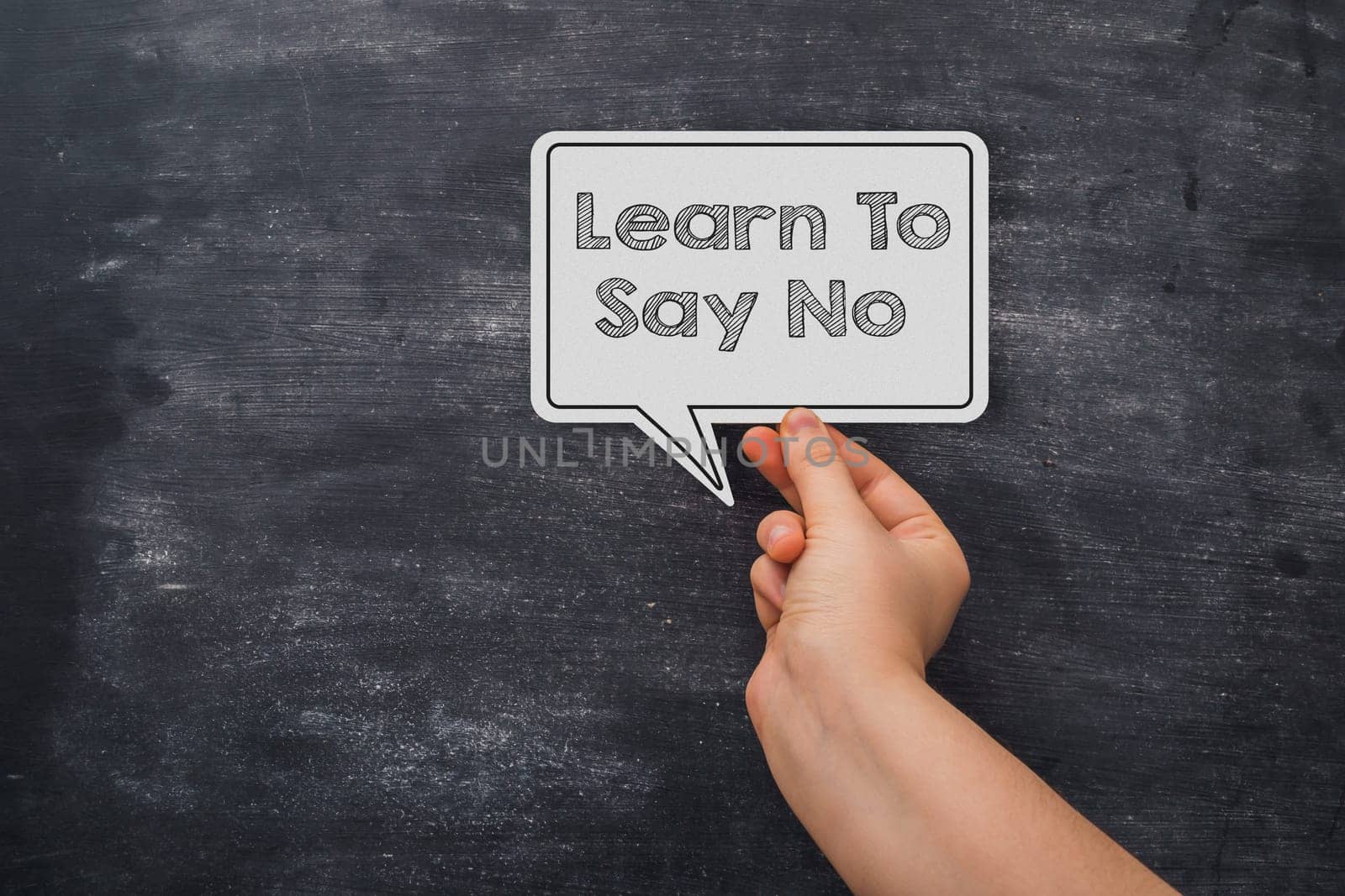 A hand holding a white paper with the words learn to say no written on it. Concept of learning to say no and the importance of standing up for oneself