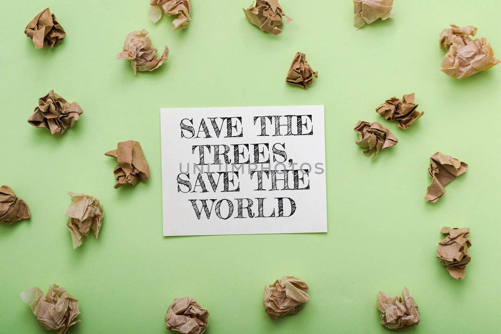 Save the trees save the world. The paper is crumpled and torn. The paper is on a green background