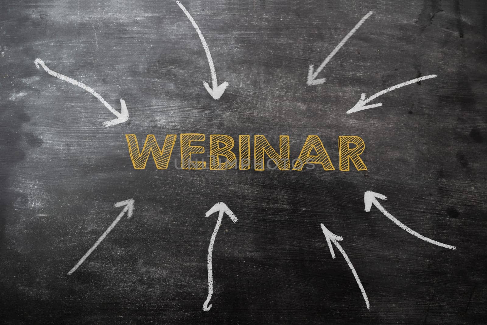 A chalkboard with a webinar written in yellow. The arrows are pointing to the word webinar