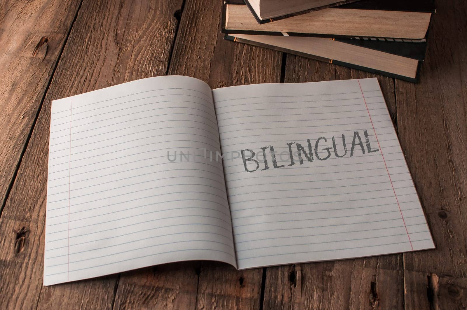A notebook is open to a page with the word bilingual written on it. The notebook is sitting on a wooden table