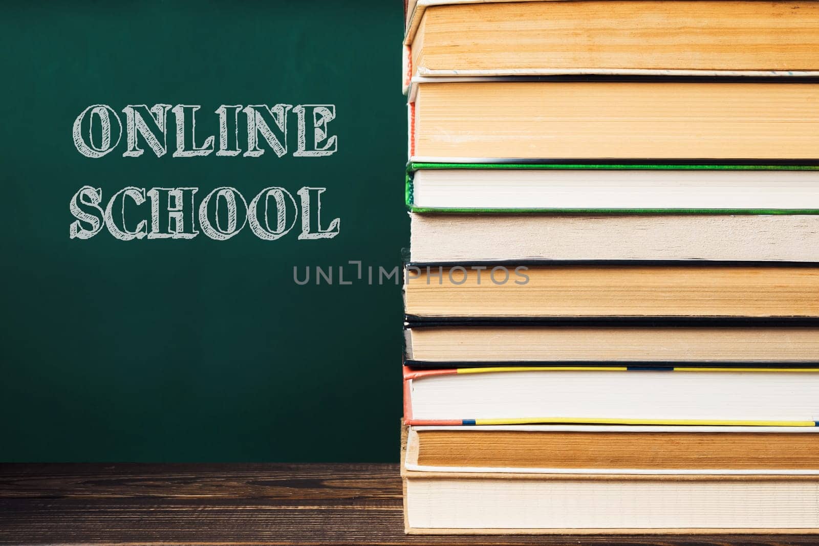 A stack of books with the word online school written on a chalkboard behind them. The books are piled on top of each other, creating a sense of importance and education