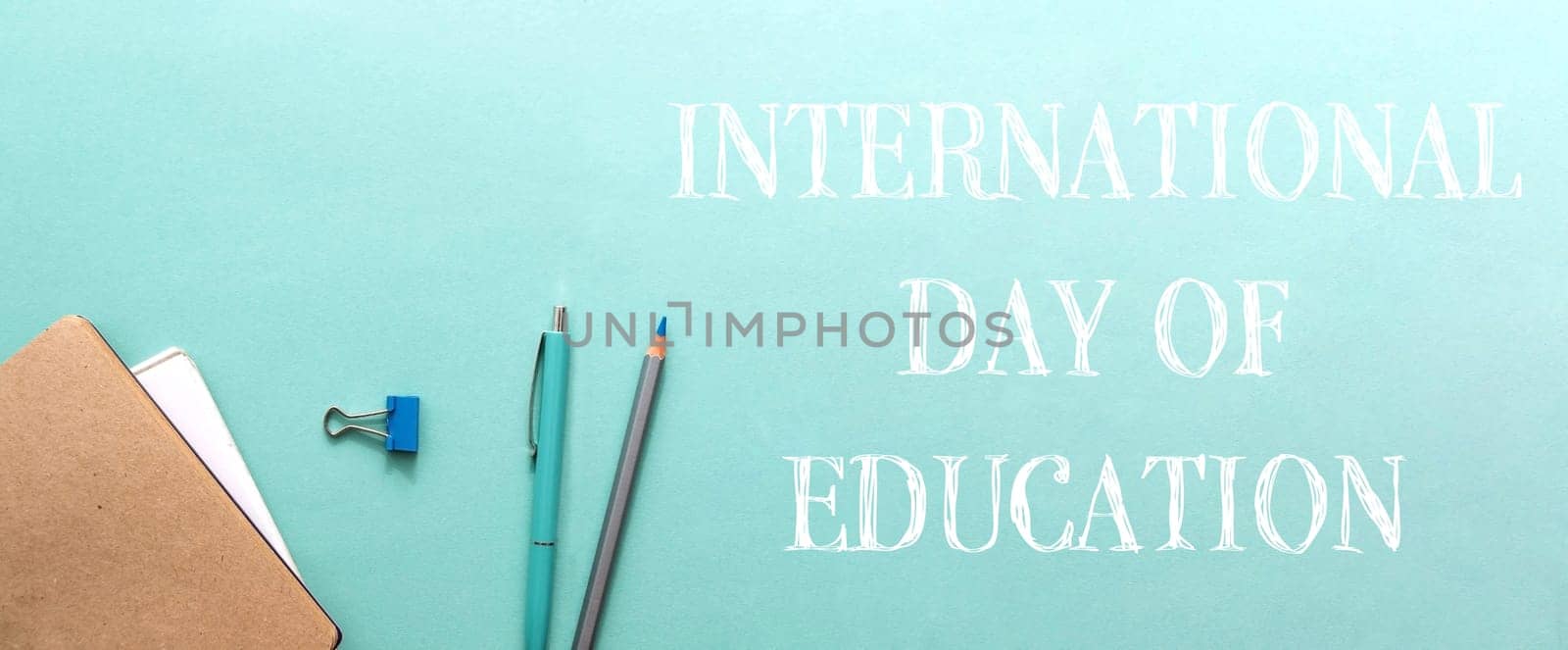 A blue background with a pencil and pen on it. The words International Day of Education are written below the pencils