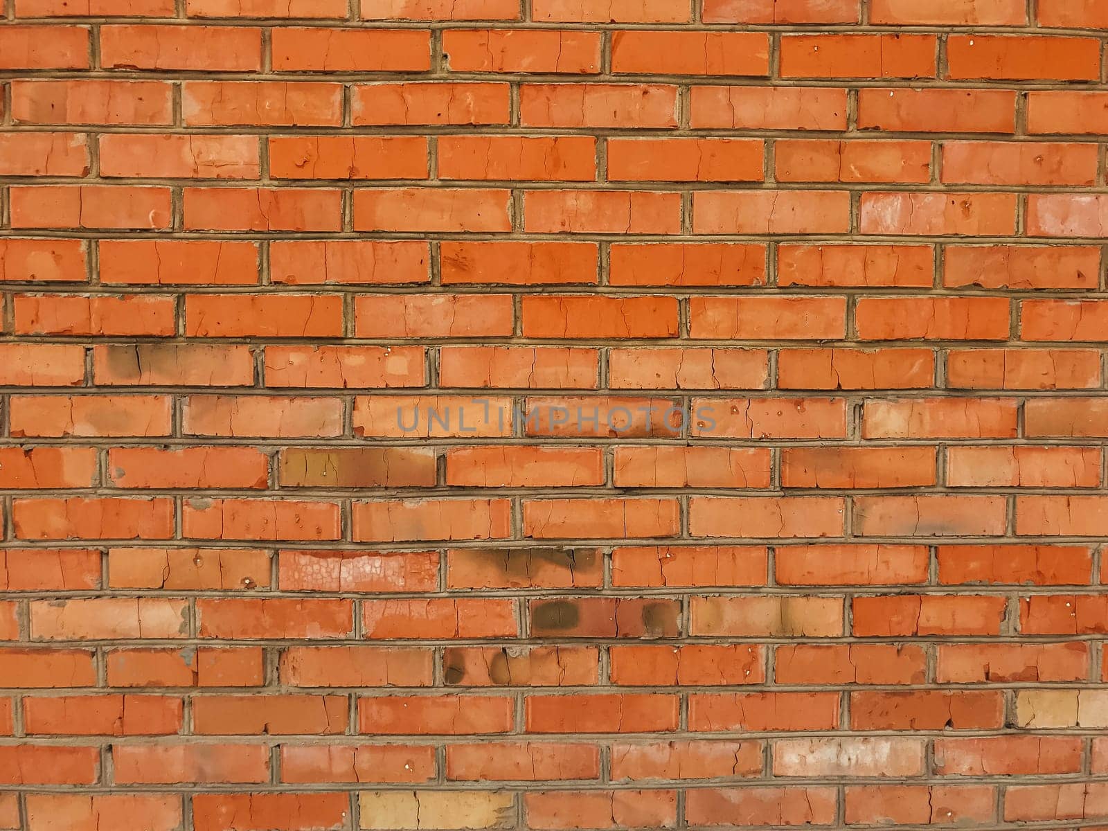 A brick wall with a red color. The wall is made of bricks and has a rough texture