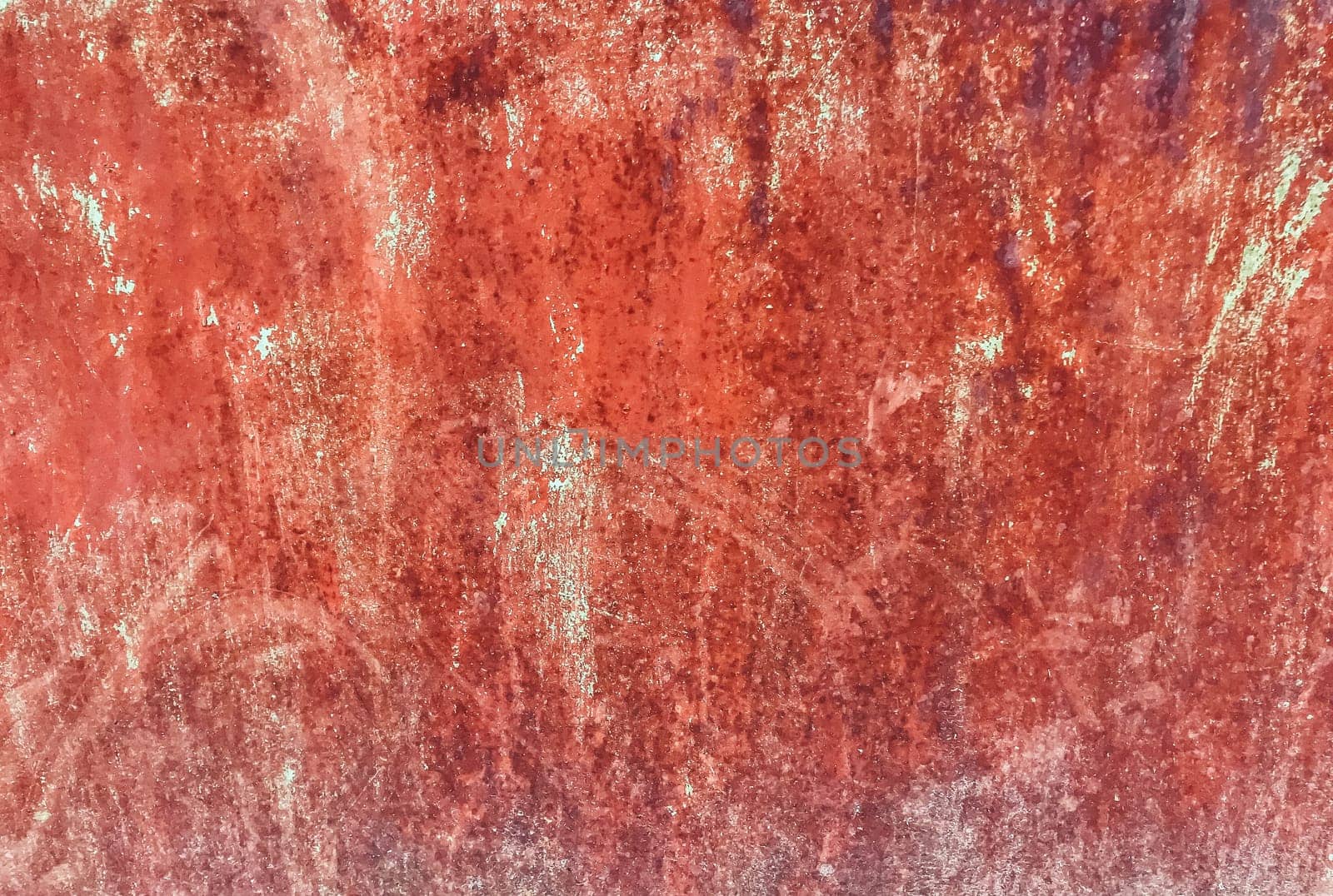 A red wall with a lot of dirt and grime on it. The wall is old and worn, with a rough texture
