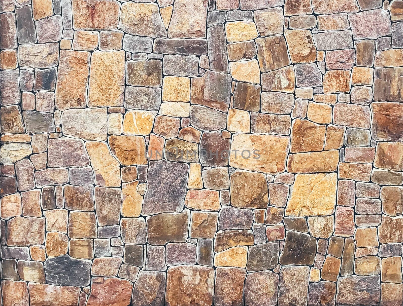 A wall made of stone blocks with a brown and tan color. The wall is very large and has a rough texture
