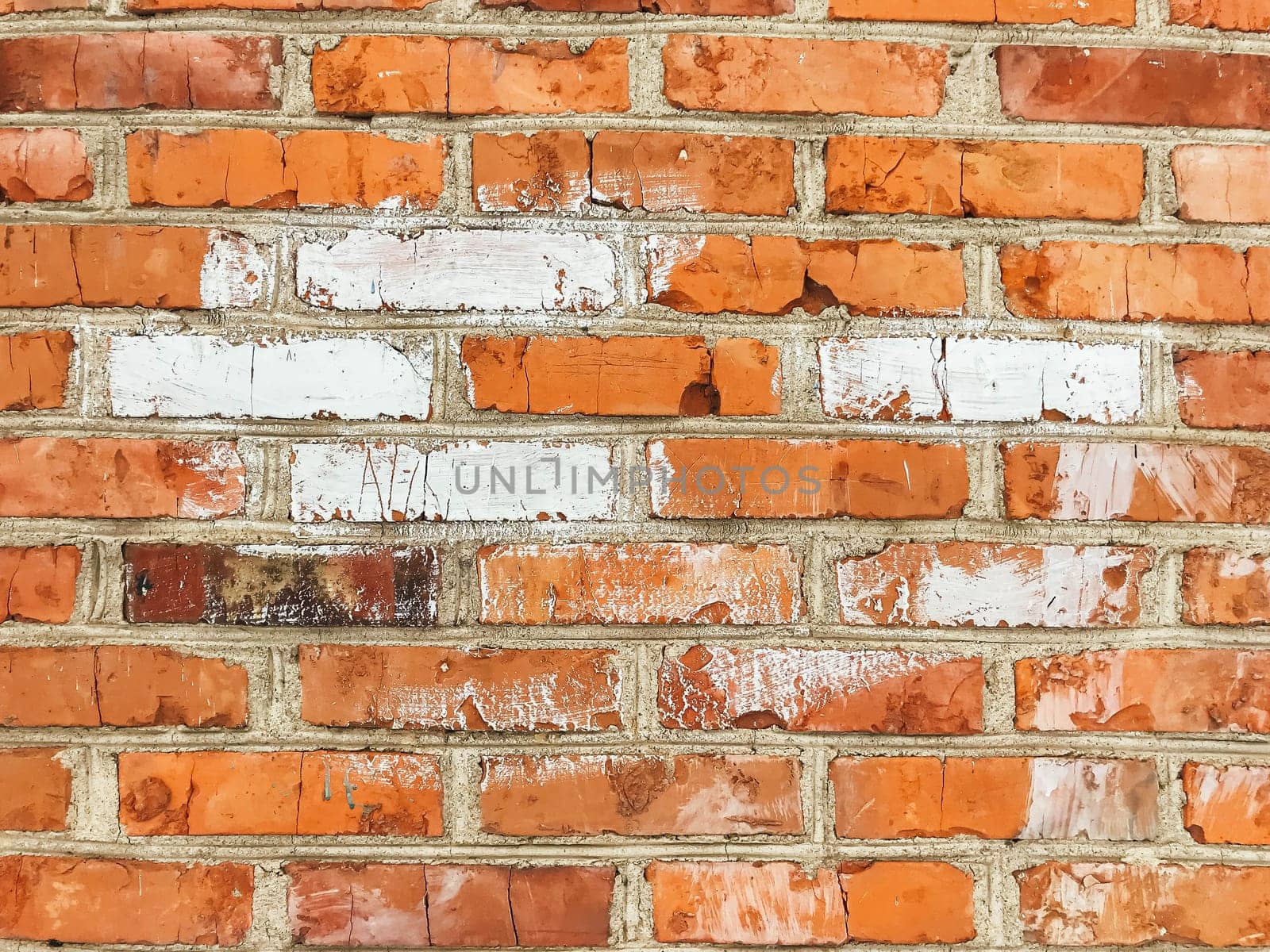 A brick wall with a white line painted on it. The white line is in the middle of the wall and is surrounded by red bricks. The wall appears to be old and worn, with some of the bricks missing