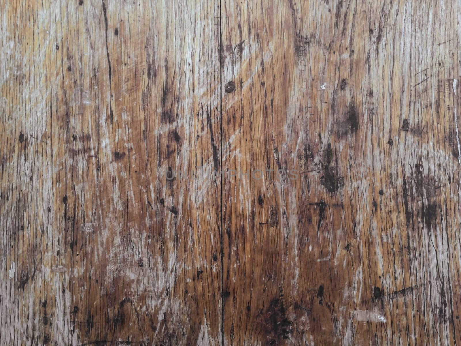 The image is of a wooden surface with a lot of scratches and marks. The surface appears to be old and worn, giving it a sense of history and character