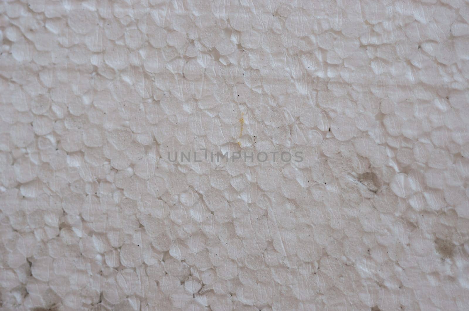 A white foam wall with a pattern of small white circles. The wall is covered in foam and has a rough texture