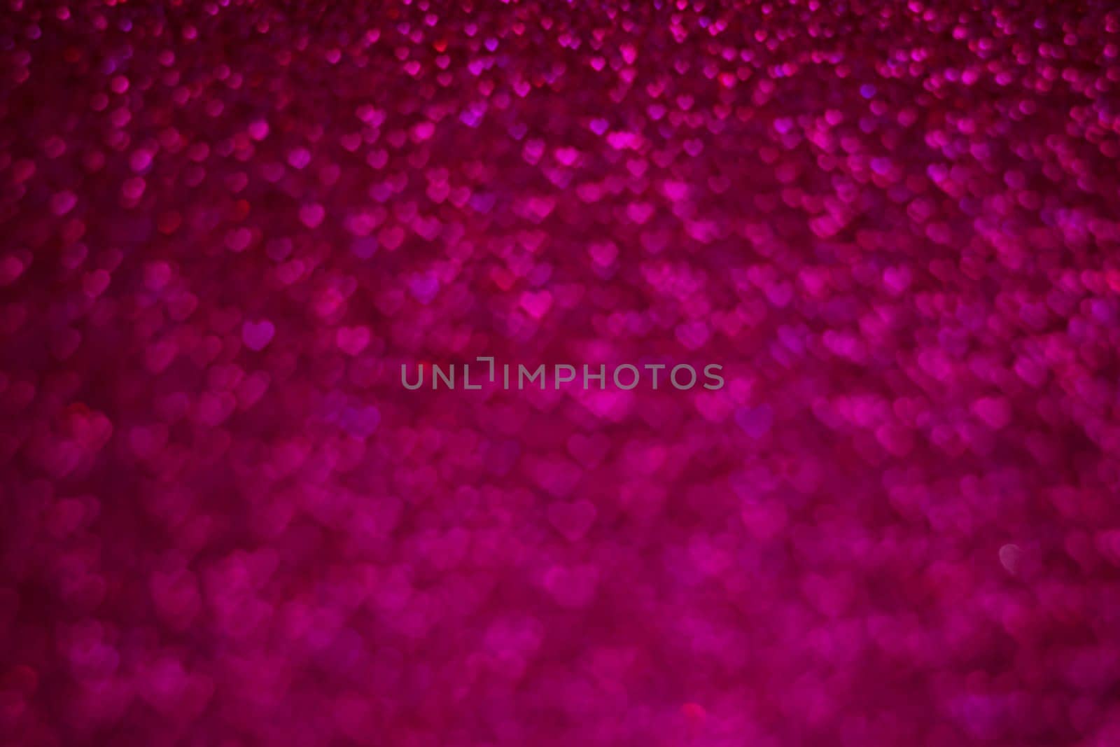 A close up of a pink background with many small hearts scattered throughout. The image has a romantic and dreamy feel to it