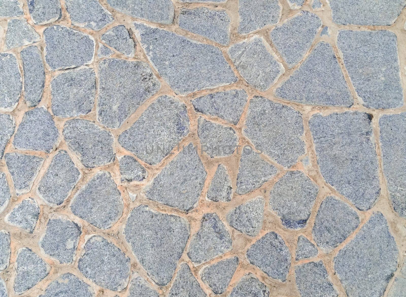 A stone wall with a lot of small stones. The wall is gray and has a rough texture