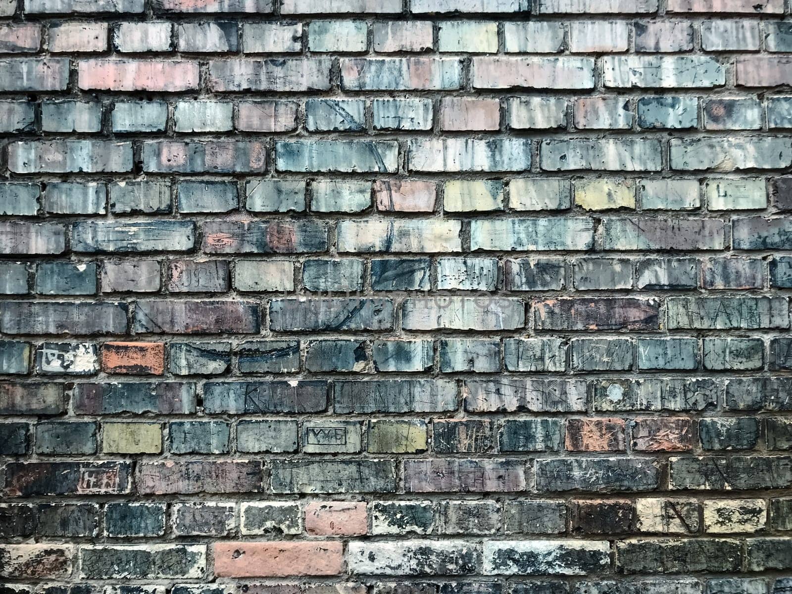 A brick wall with a blue and pink color. The wall is old and has a lot of cracks